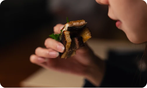 手に持った一口サイズの料理を食べようとしている様子